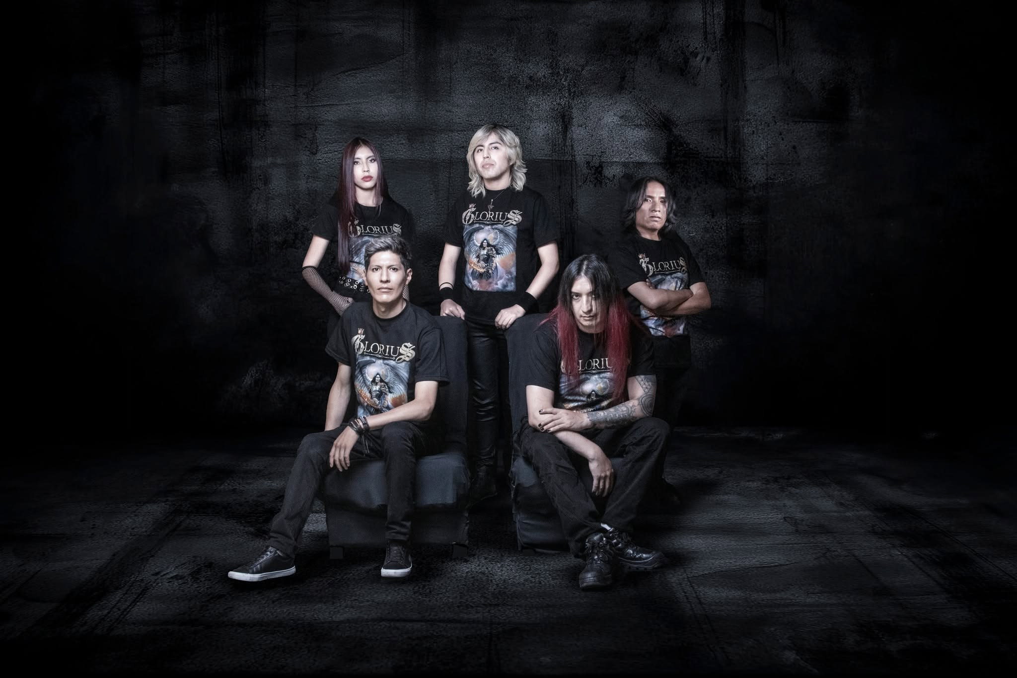 Fotografía de los cinco integrantes de GLORIUS con camisetas de la banda, en un estudio de fondo oscuro